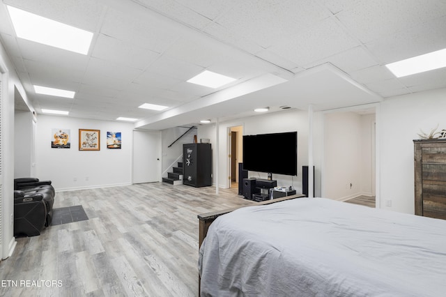 bedroom with light wood-type flooring and a drop ceiling