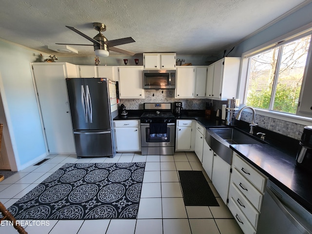 kitchen featuring appliances with stainless steel finishes, tasteful backsplash, ceiling fan, sink, and white cabinetry