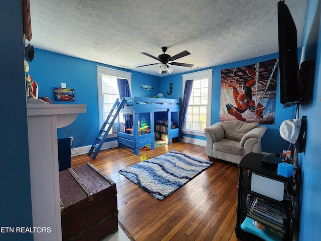 bedroom with hardwood / wood-style floors, ceiling fan, a textured ceiling, and multiple windows