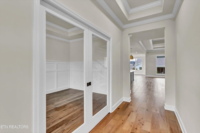 hallway with hardwood / wood-style floors, a raised ceiling, and crown molding