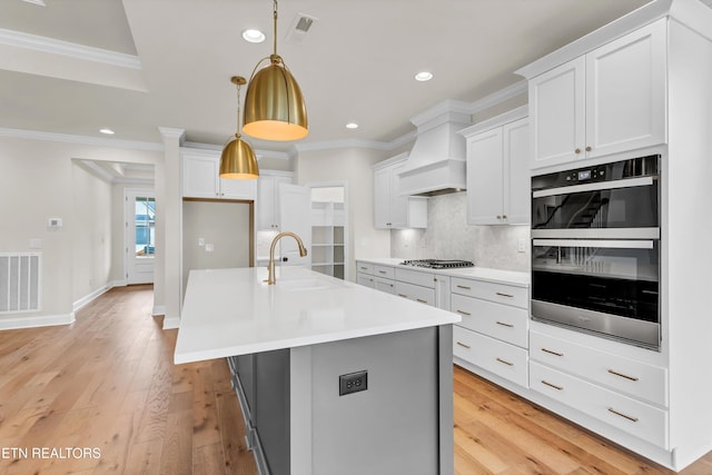 kitchen featuring white cabinetry, sink, double wall oven, and pendant lighting