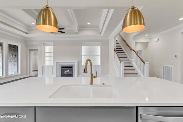 kitchen featuring decorative light fixtures, a center island with sink, crown molding, and sink