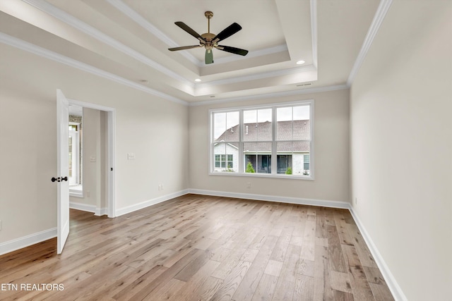 unfurnished room featuring ceiling fan, ornamental molding, light hardwood / wood-style flooring, and a tray ceiling