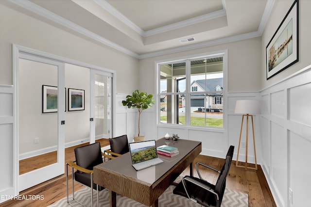 home office with hardwood / wood-style floors, a tray ceiling, and ornamental molding