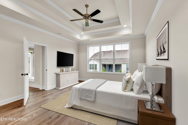 bedroom featuring a raised ceiling, ceiling fan, light hardwood / wood-style floors, and ornamental molding