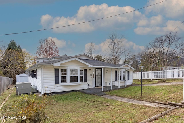 bungalow-style home featuring a front lawn, covered porch, and a shed