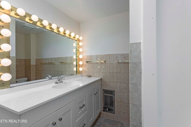 bathroom with vanity, tile patterned flooring, toilet, tile walls, and heating unit