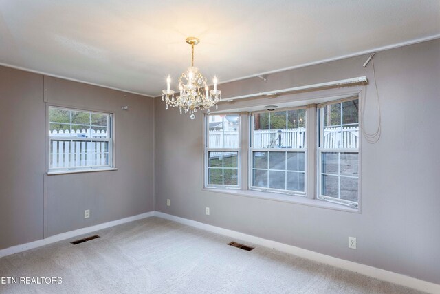 carpeted empty room featuring a notable chandelier