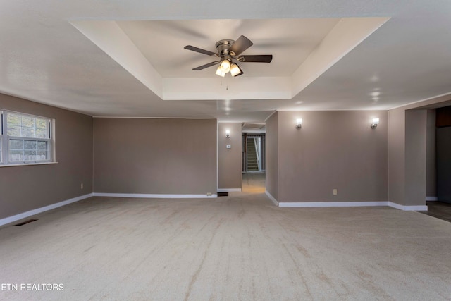 carpeted empty room featuring ceiling fan and a tray ceiling