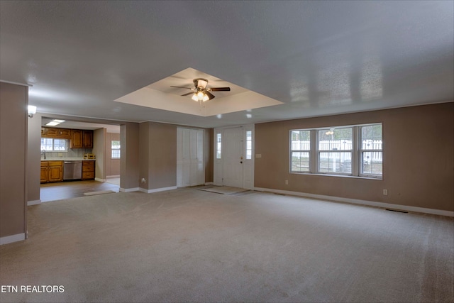 unfurnished living room featuring light carpet, a raised ceiling, and ceiling fan