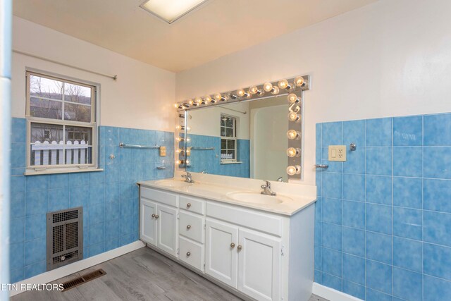 bathroom featuring heating unit, vanity, wood-type flooring, and tile walls