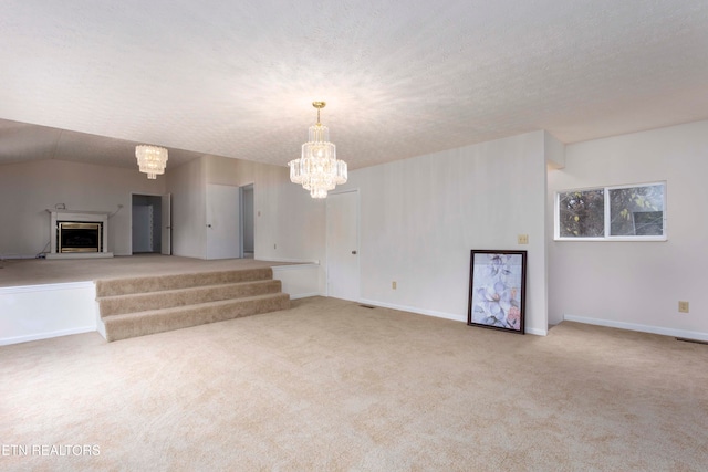 unfurnished living room featuring light carpet, a textured ceiling, lofted ceiling, and a notable chandelier