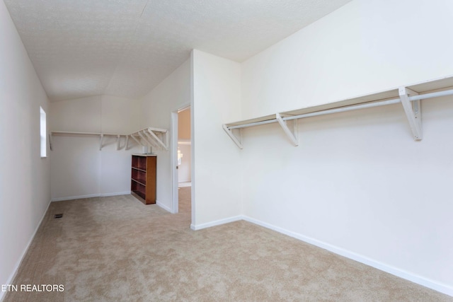 walk in closet featuring light carpet and vaulted ceiling