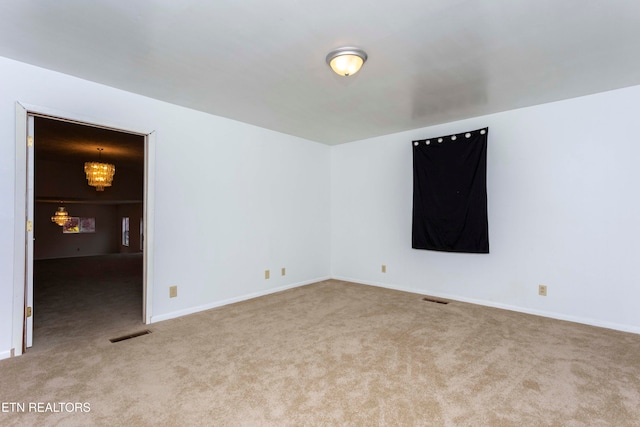 carpeted spare room with a chandelier