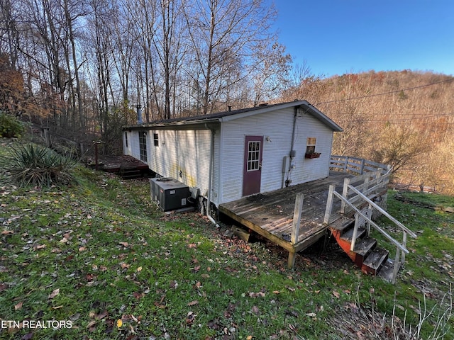 back of property with a deck, a yard, and central AC