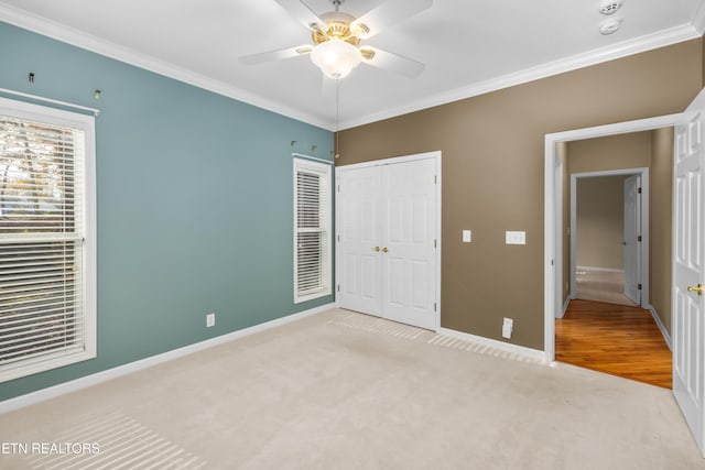 unfurnished bedroom with light carpet, a closet, ceiling fan, and ornamental molding