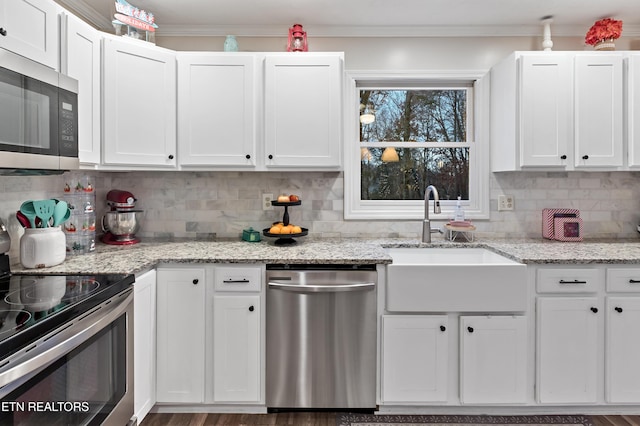 kitchen featuring ornamental molding, decorative backsplash, appliances with stainless steel finishes, white cabinetry, and a sink