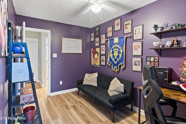 office area featuring baseboards, a textured ceiling, light wood-style flooring, and a ceiling fan