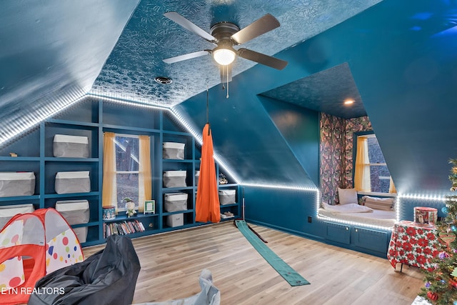 bedroom featuring lofted ceiling, a textured ceiling, wood finished floors, and a ceiling fan