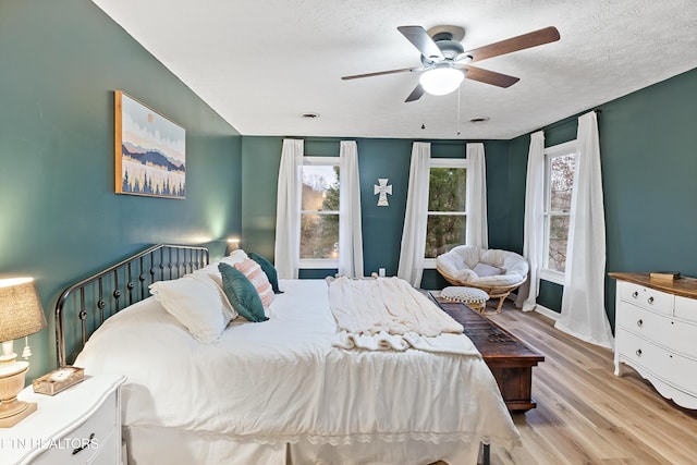 bedroom with a textured ceiling, wood finished floors, and a ceiling fan