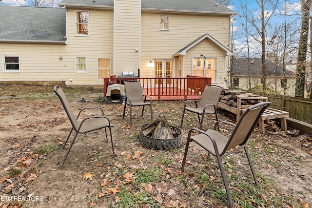 rear view of house featuring french doors, a fire pit, a deck, and a shingled roof