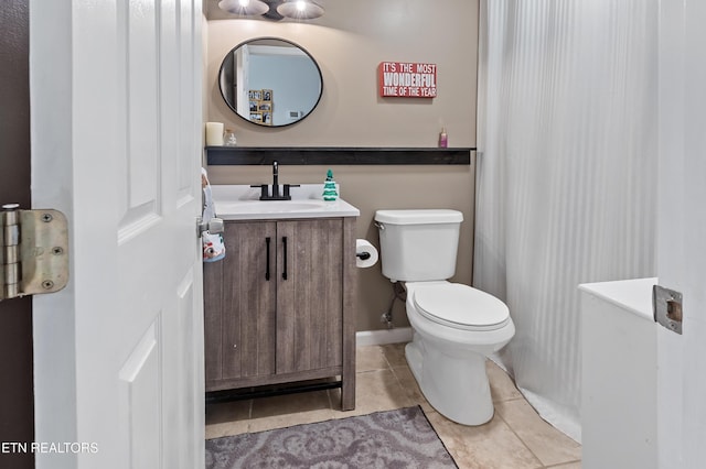 half bath with tile patterned flooring, toilet, vanity, and baseboards