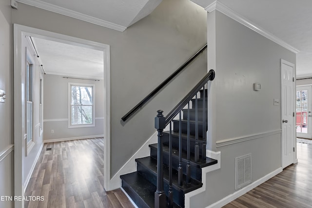 stairs featuring visible vents, plenty of natural light, wood finished floors, and crown molding