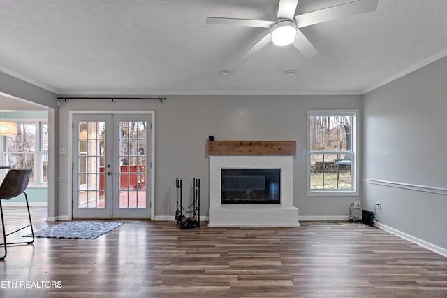 unfurnished living room featuring crown molding, baseboards, french doors, wood finished floors, and a glass covered fireplace