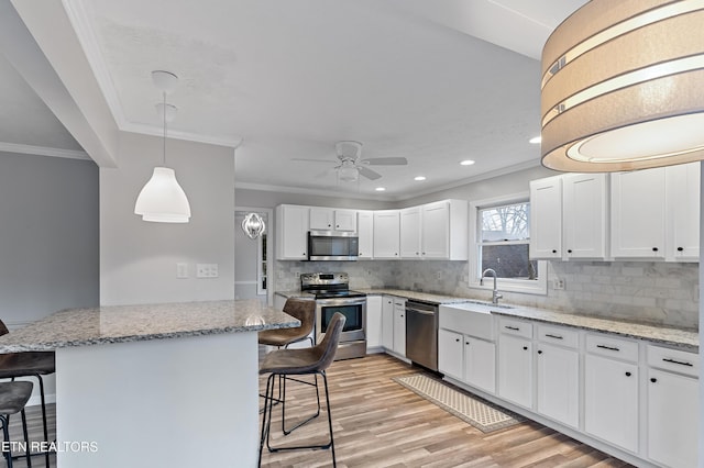 kitchen featuring white cabinetry, appliances with stainless steel finishes, a breakfast bar, and light wood-style floors