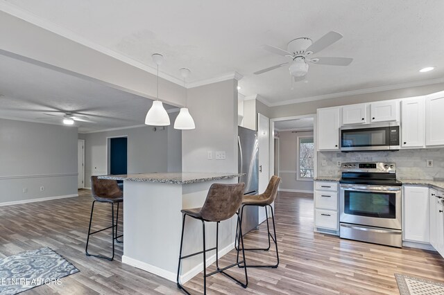 kitchen with tasteful backsplash, light stone countertops, a breakfast bar area, appliances with stainless steel finishes, and white cabinetry