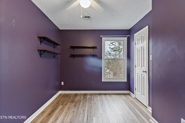 entryway with baseboards, wood finished floors, visible vents, and a textured ceiling