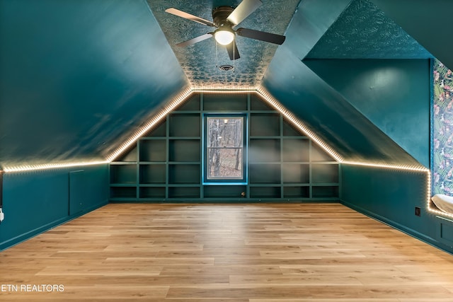 bonus room with ceiling fan, built in shelves, lofted ceiling, and wood finished floors