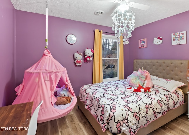 bedroom featuring a chandelier, visible vents, a textured ceiling, and wood finished floors