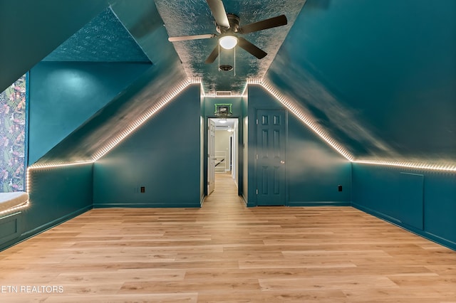 additional living space featuring baseboards, a ceiling fan, lofted ceiling, and wood finished floors