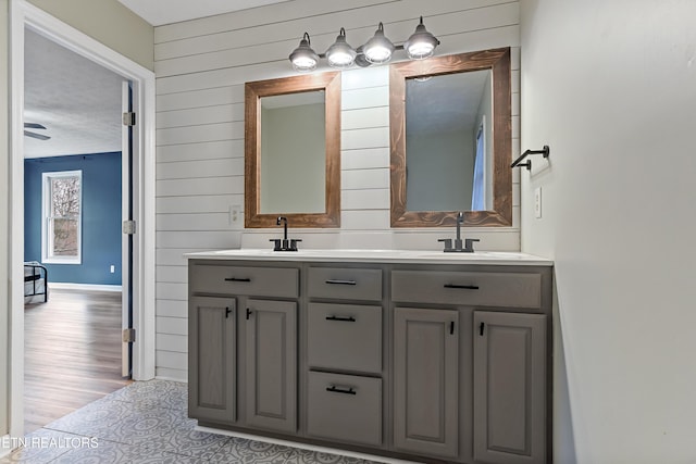 bathroom featuring double vanity, wood finished floors, wood walls, and a sink