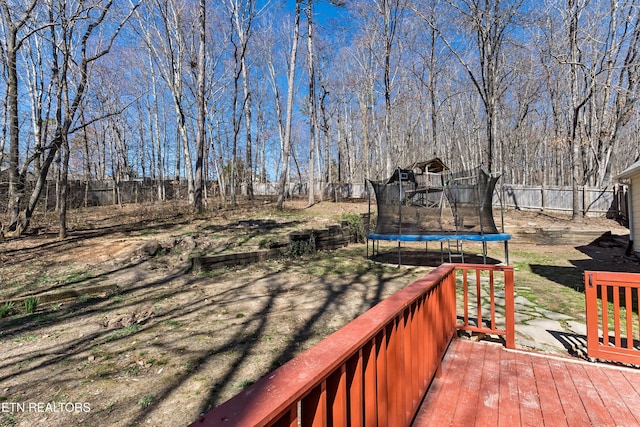 wooden terrace featuring a trampoline and fence