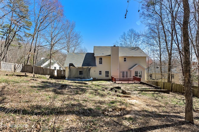 back of property featuring a fenced backyard, a deck, and a trampoline