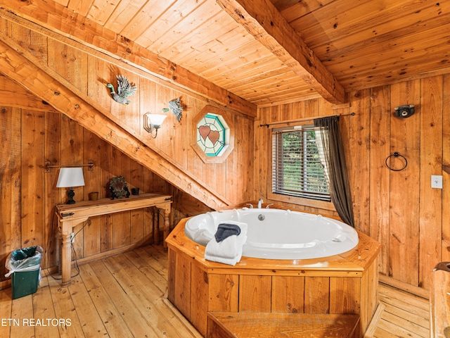 bathroom featuring wood walls, wooden ceiling, a bathing tub, beamed ceiling, and wood-type flooring