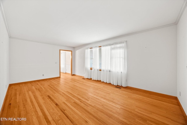 spare room with ornamental molding and light wood-type flooring