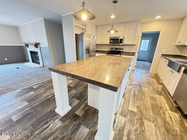 kitchen featuring a kitchen breakfast bar, stainless steel appliances, white cabinets, a kitchen island, and hanging light fixtures