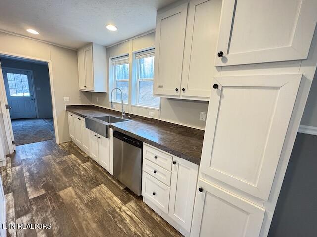 kitchen with dark wood-type flooring, sink, stainless steel dishwasher, a textured ceiling, and white cabinetry