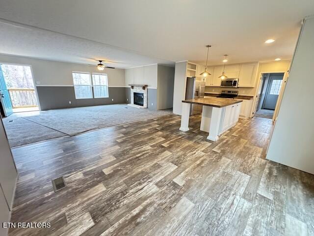 kitchen featuring a center island, white cabinets, ceiling fan, wood-type flooring, and stainless steel appliances