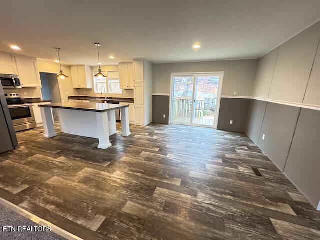 kitchen with pendant lighting, white cabinets, stainless steel appliances, and a kitchen island