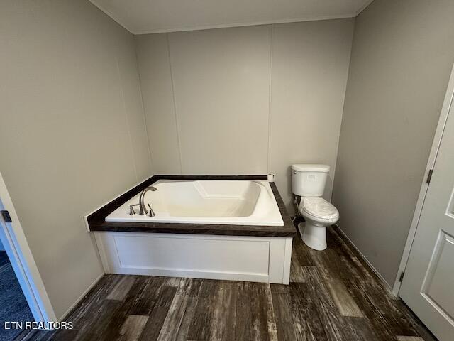 bathroom featuring crown molding, toilet, wood-type flooring, and a bath