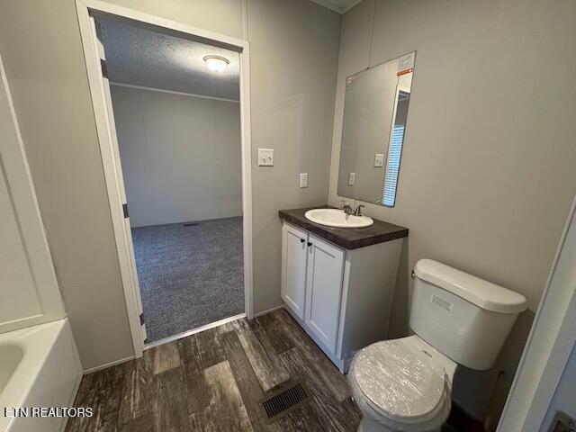 bathroom with vanity, toilet, wood-type flooring, and a tub