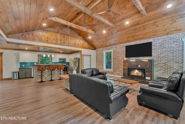 living room with beam ceiling, light hardwood / wood-style floors, wooden ceiling, and brick wall