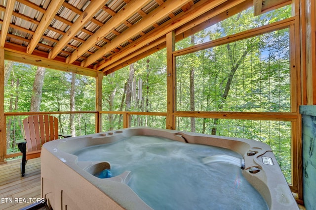 sunroom / solarium with vaulted ceiling, a hot tub, and a wealth of natural light