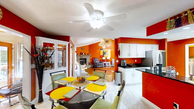 dining area featuring ceiling fan, washer / clothes dryer, lofted ceiling, a textured ceiling, and a fireplace