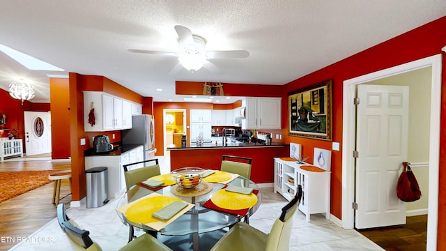 kitchen featuring stainless steel fridge, light wood-type flooring, a textured ceiling, ceiling fan, and white cabinetry