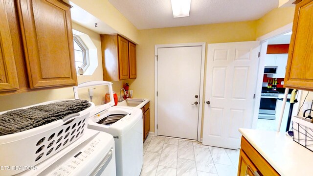 clothes washing area featuring washer and clothes dryer, cabinets, and sink